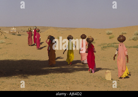 Rajasthani-Frauen, die Wasser auf dem Kopf von einer Wüste weit außerhalb Jaisalmer, Rajasthan, Indien tragen. Stockfoto