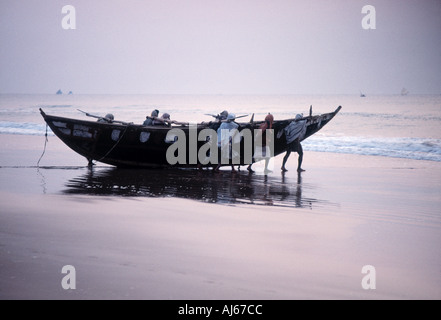 Fischer, die ihr Boot vom Strand entfernt in der Morgendämmerung starten Stockfoto