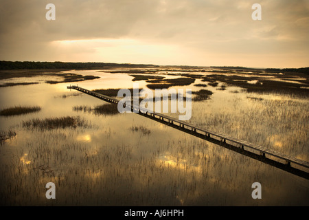 Malerische Holzsteg erstreckt sich über Feuchtgebiete bei Sonnenuntergang auf Bald Head Island North Carolina Stockfoto