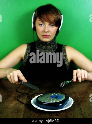 Frau sitzt am Tisch mit CD-Spieler auf einem Teller. Stockfoto