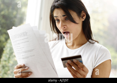 Ethnische Frau schockiert auf Rechnung Stockfoto