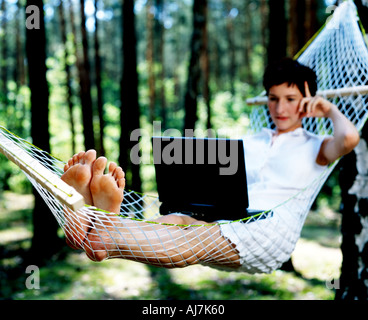 Frau sitzt in einer Hängematte und ihrem Computer verwenden. Stockfoto