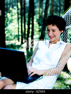 Frau sitzt in einer Hängematte und ihrem Computer verwenden. Stockfoto