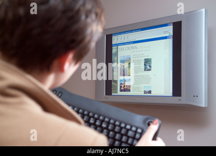 Frau mit Funktastatur mit Wand montierte Computer-Bildschirm Stockfoto