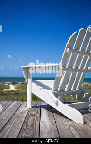 Leere weiße Adirondack Stuhl auf Holzterrasse mit Blick auf Strand Stockfoto