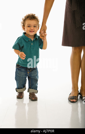 African American Kleinkind Jungen Mutter Hand lächelnd auf Betrachter festhalten Stockfoto