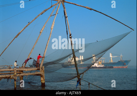 Containerschiff vorbei ein traditionelles freitragend Chinesen Angeln Net, Fort Cochin, Kochi (Cochin), Kerala, Indien Stockfoto