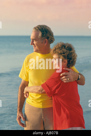 Älteres paar umarmt am Strand Stockfoto