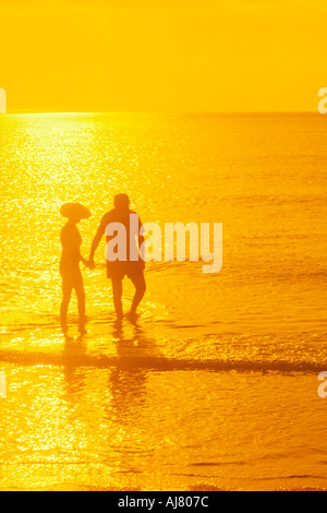 Silhouette der Reifen Urlaub paar waten im Meer bei Sonnenuntergang in warmem Wasser Stockfoto