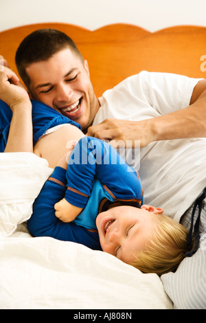 Kaukasische Kleinkind Jungen und Vater spielen und kitzeln im Bett Stockfoto