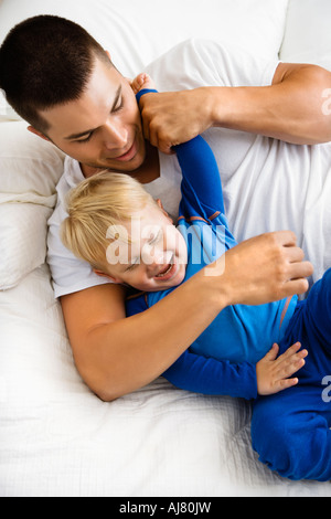 Kaukasische Kleinkind Jungen und Vater spielen und kitzeln im Bett Stockfoto