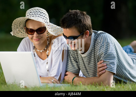 Ein modernes junges Paar außerhalb in einer Waldlichtung mit einem Laptopcomputer Stockfoto