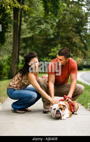 Kaukasischen Mitte erwachsenes paar streicheln englische Bulldogge auf Bürgersteig Stockfoto