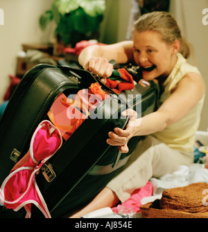 Frau kämpft Koffer im Schlafzimmer zu tun, bis Stockfoto