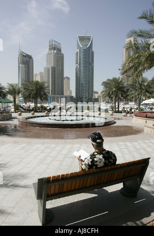 Touristen sitzen auf einer Bank an der Dubai Marina einen Reiseführer lesen. Stockfoto