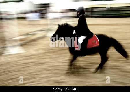 verschwommenes Bild von Youngster auf einem Pony in einer Reitschule Stockfoto