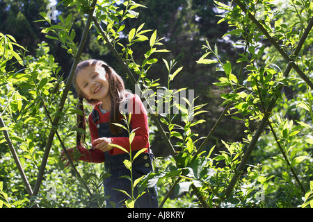 Mädchen (5-6) steht im Obstgarten, Lächeln, Porträt Stockfoto