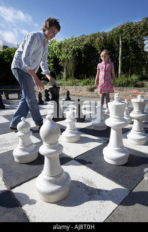 Mädchen im Alter von 9 und jungen im Alter von 15 spielen Schach auf ein Riese auf einem Grundstück von Burton Agnes Hall East Yorkshire UK Stockfoto