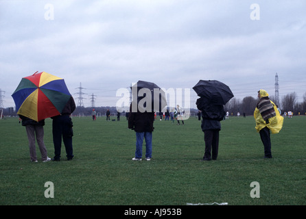 Zuschauer bei Regen und Wind beobachten ein Sonntag Liga Fußballspiel auf Sümpfe Hackney, London, UK. Stockfoto