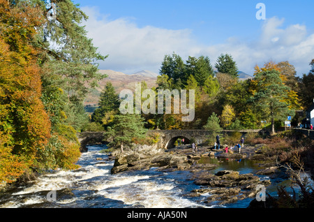 Mehrere kleine Wasserfälle Die Wasserfälle von Dochart auf dem Fluss Dochart bei Killin Schottland mit dem Fluss Dochart Brücke an einem sonnigen Herbsttag Stockfoto