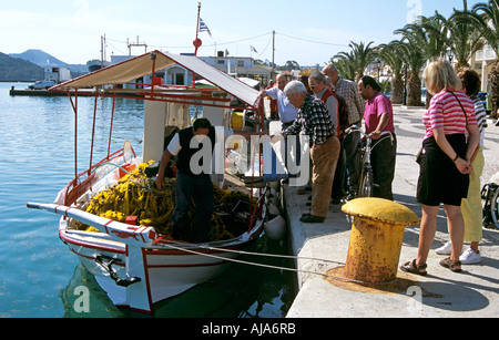 Mann kaufen Fisch vom Fischer am Fischerboot, Touristen auf Kai, Argostoli, Kefalonia, Griechenland Stockfoto