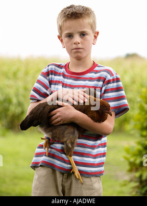 Ernsthafte Suche junge im gestreiften Hemd hielt Huhn in seinen Armen Ruurlo Gelderland Niederlande Stockfoto