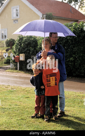 Familie Cought heraus in einem Sommer-Regen geht in Deckung unter einem Regenschirm Stockfoto