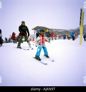 Whistler Mountain, BC, Britisch-Kolumbien, Kanada-junge Mädchen lernen, Ski ohne Stöcke, Vater halten Harness Stockfoto