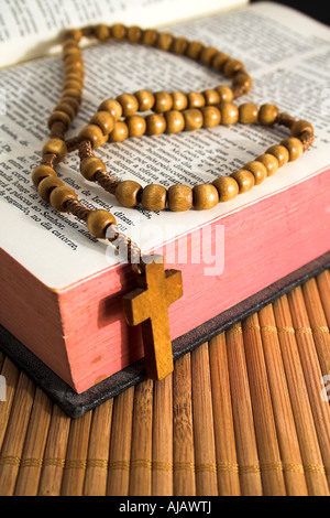 Aufgeschlagene Bibel mit Rosenkranz auf dem Stroh Tisch Stockfoto