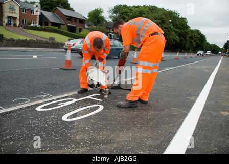 Männer bei der Arbeit: Fahrbahnmarkierungen.  Zwei Männer in orange hi-Vis passt ein Radweg mit Farbe markieren. Stockfoto