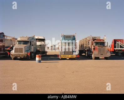 Große amerikanische Juggernauts geparkt neben einander in einem Truck Stop in der Wüste, einige Anzeigen eines "Oversize Load"-Banners. Stockfoto