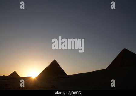 Von Khufu Cheops-Pyramide mit Pyramiden von Khafre Chefren und Menkaure Mycerinus in der Silhouette bei Sonnenuntergang Gizeh Kairo Ägypten A Stockfoto