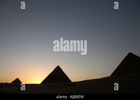 Von Khufu Cheops-Pyramide mit Pyramiden von Khafre Chefren und Menkaure Mycerinus in der Silhouette bei Sonnenuntergang Gizeh Kairo Ägypten A Stockfoto