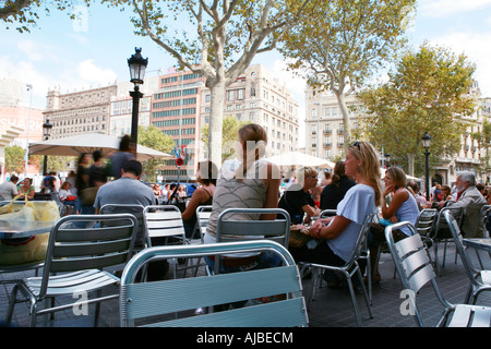 Menschen sitzen vor einer Bar an der Playa de Catalunya in Barcelona, Spanien Stockfoto