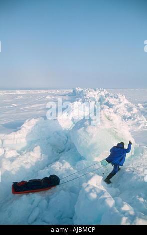 Einsamer Skifahrer zieht einen Schlitten über eine Schnee-Brücke Stockfoto