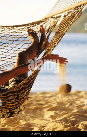 Frau in Hängematte mit Strandsand durch die Finger tropft Stockfoto