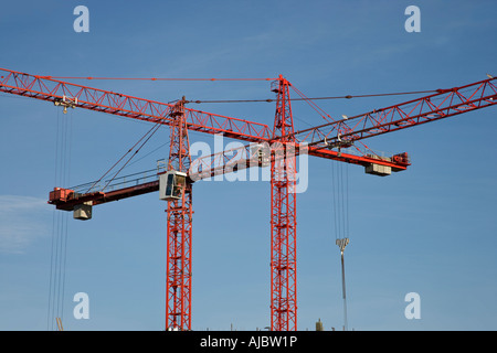 2 rote überlappende Krane auf Baustelle vor blauem Himmel Stockfoto