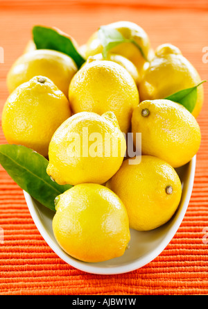 Große Schale mit glänzenden Zitronen mit orangem Hintergrund Stockfoto