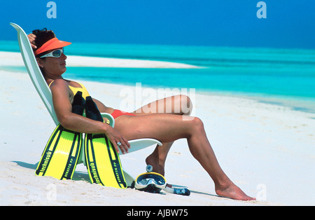 junge Frau sitzt auf Liegestuhl am Strand, Sonne, Sonnenbrille, Schnorcheln Ausrüstung Stockfoto