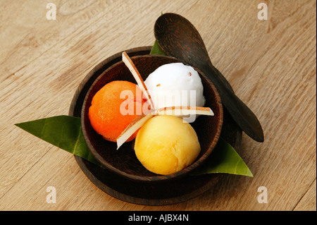 Lichi, Mango und Orange aromatisiert Sorbet Eisportionierer in einer Holzschale Stockfoto