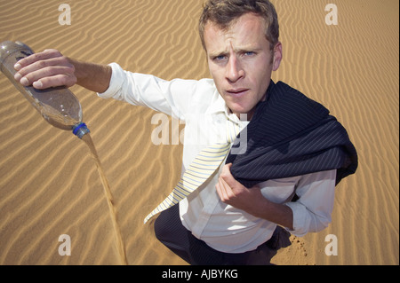 Geschäftsmann Gießen Sand aus einer Wasserflasche Stockfoto