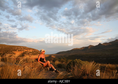 Frau sitzt auf einem Felsen, den Sonnenuntergang beobachten Stockfoto