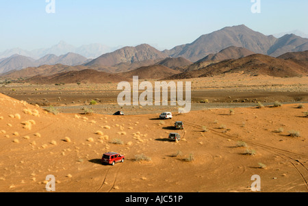 Ein Konvoi von 4 x 4 Fahrzeuge mit dem Hajar-Gebirge im Hintergrund Stockfoto