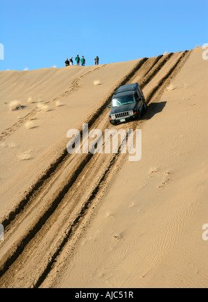 4 x 4 Fahrzeug fahren auf einer großen Düne mit Silhouette Menschen an der Spitze Stockfoto