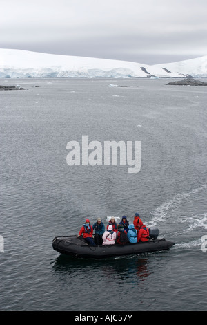 Blick auf Touristen in ein Schlauchboot mit einem Eisberg im Hintergrund - High Angle View Stockfoto