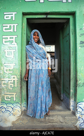 Eine indische Frau in einem bunten Ari steht vor der Tür in ihre Khajuraho alte Heimatstadt Madhya Pradesh, Indien Stockfoto