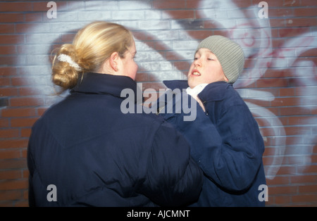 ein junges Mädchen treibt einen jüngeren Jungen gegen eine Wand, die ihn Würgen Stockfoto