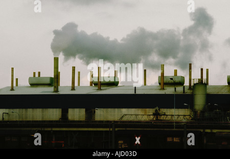 Düsteres Ambiente mit alter Fabrik, die umweltschädlichen Rauch aus einem Schornstein aussendet. Stockfoto