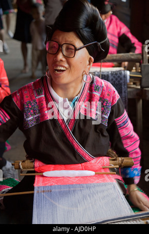 Yao-Frau Lachen als sie sitzt an ihrem Webstuhl Stockfoto