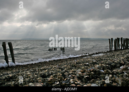 Southampton Water, einem hölzernen Buhne und Strand Kieselsteine Satz gegen eine imposante Himmel bei Calshot Spit, Calshot, Hampshire Stockfoto